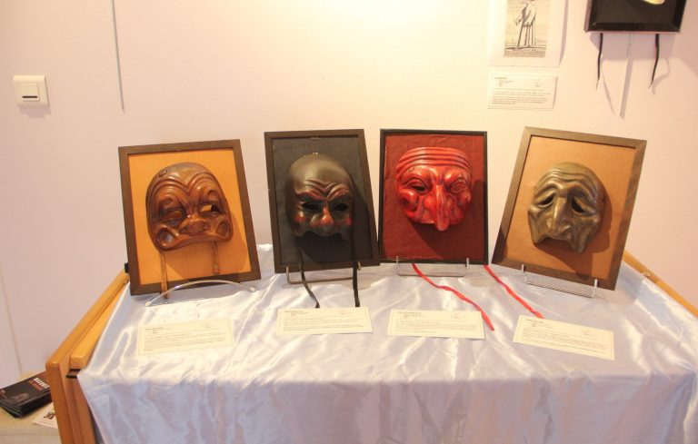 Masques en latex représentant différents visages, alignés sur un mur.