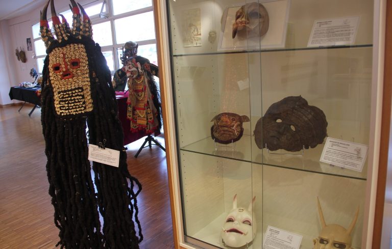 Masques en plastique représentant différents visages humains, exposés sur un mur.