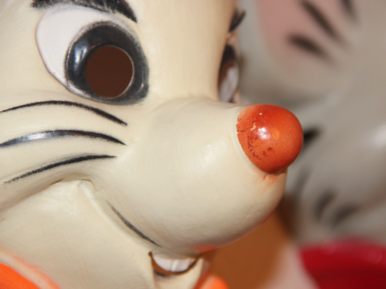 Sourire d'une figurine de souris en plastique avec un nez orange et des moustaches.